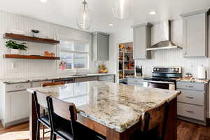 Kitchen with gray cabinetry, a kitchen breakfast bar, and light stone counters