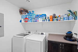 Laundry room with separate washer and dryer, cabinet space, and electric panel