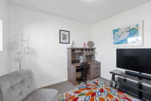 Bedroom featuring dark colored carpet and an office area