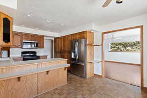 Kitchen with ceiling fan, stainless steel appliances, light countertops, parquet floors, and a peninsula