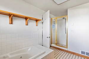 Bathroom featuring a stall shower, a tub with jets, and light tile patterned floors