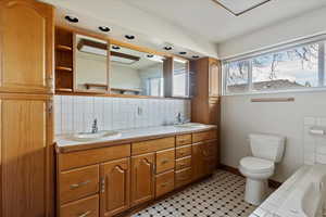 Full bathroom featuring tasteful backsplash, double vanity, and a bath
