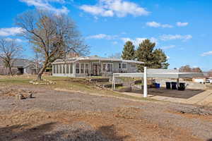 View of front facade with a detached carport, a sunroom, a patio area, and driveway