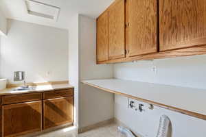 Laundry area featuring light tile patterned floors, cabinet space, and washer hookup