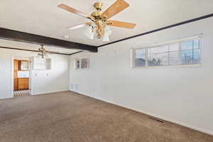 Empty room with a textured ceiling, carpet flooring, ceiling fan, and beam ceiling