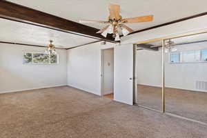 Unfurnished bedroom featuring light colored carpet, ornamental molding, a textured ceiling, a closet, and a ceiling fan