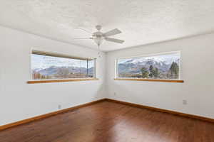 Spare room with dark wood finished floors, a ceiling fan, a mountain view, and a textured ceiling