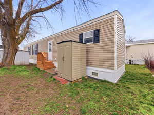 Back of house with a shed and a yard