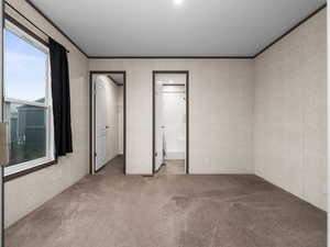 Unfurnished bedroom with a walk in closet, carpet, crown molding, recessed lighting, and connected bathroom