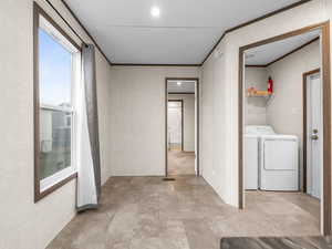 Laundry area with washer and dryer, ornamental molding, recessed lighting, and stone finish flooring