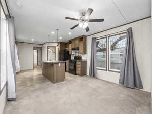 Kitchen featuring black appliances, a kitchen island, wood finish cabinets, light colored carpet, and a ceiling fan