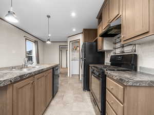 Kitchen featuring black appliances, dark countertops, washer / clothes dryer, pendant lighting, and ornamental molding