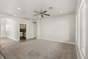 Empty room with arched walkways, recessed lighting, a ceiling fan, and light colored carpet