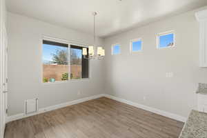 Unfurnished dining area with light wood-style floors and suspended lighting