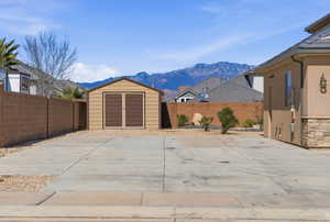 Fenced backyard featuring a storage shed and a mountain view