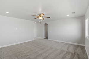 Unfurnished room with arched walkways, light colored carpet, a ceiling fan, and recessed lighting