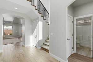 Staircase featuring wood finish floors, arched walkways, ceiling fan, and recessed lighting