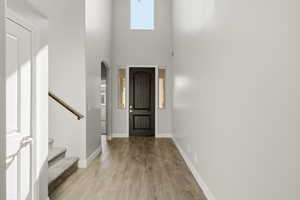Entryway featuring light wood finished floors, a high ceiling, arched walkways, and healthy amount of natural light