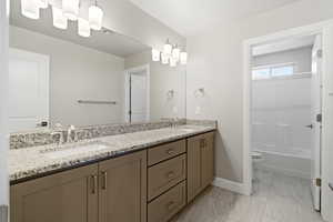 Bathroom with double vanity and light marble finish flooring