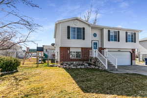 Split foyer home featuring brick siding, a gate, a garage, and concrete driveway