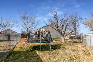 Fenced backyard featuring a trampoline and a residential view