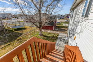 Wooden deck with a trampoline, a residential view, a fenced backyard, and a shed