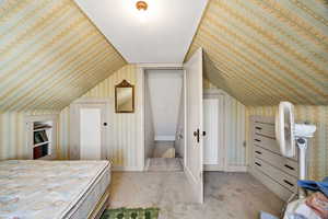 Bedroom featuring carpet, wallpapered walls, and lofted ceiling