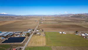 Aerial view of property and surrounding area featuring rural landscape, mountains, and farmland