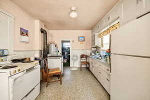 Kitchen with white appliances, white cabinetry, light countertops, and water heater