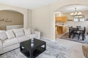 Living area with arched walkways, light colored carpet, and hanging lights