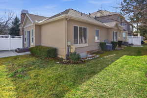 View of side of home with stucco siding, a shingled roof, and a chimney