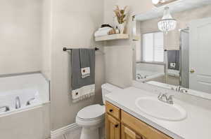Bathroom with a bath, vanity, light tile patterned floors, and suspended lighting