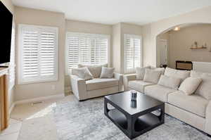 Carpeted living room featuring arched walkways and baseboards