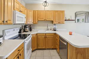 Kitchen featuring white appliances, a peninsula, and light countertops