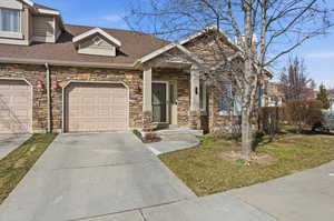 View of front of property with stone siding, driveway, and roof with shingles