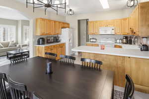 Kitchen with light countertops, white appliances, a peninsula, and light wood finish cabinets