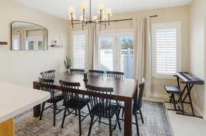 Dining room featuring hanging lights, healthy amount of natural light, and light colored carpet