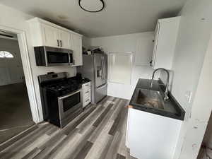 Kitchen featuring white cabinets, stainless steel appliances, and dark wood-style floors