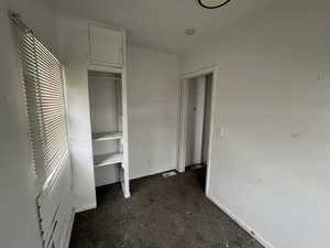 Unfurnished bedroom featuring dark colored carpet and a closet
