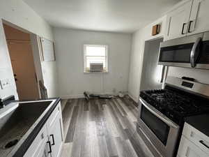 Kitchen with stainless steel appliances, white cabinetry, and dark wood-type flooring