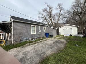 View of home's exterior with driveway, an outbuilding, a garage, and a shingled roof