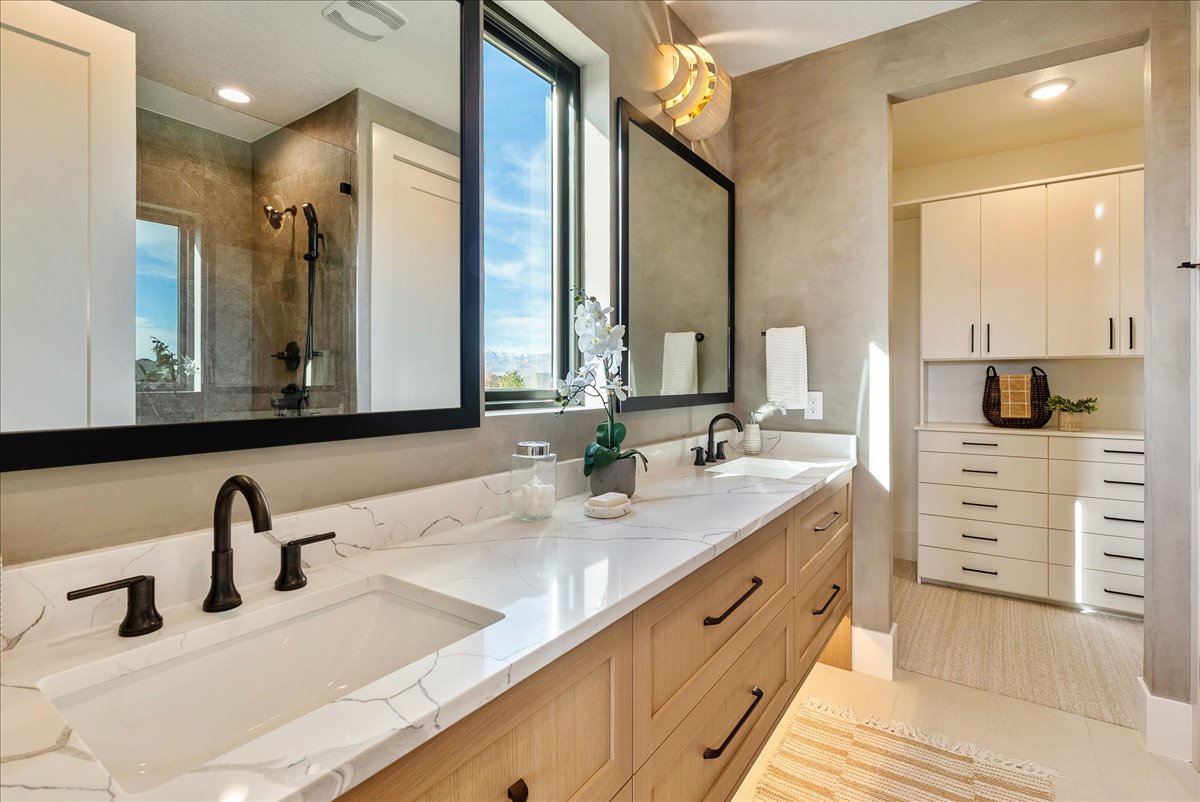 Full bathroom with double vanity, recessed lighting, and tiled shower