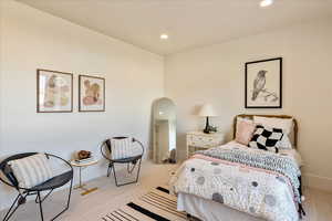 Bedroom featuring recessed lighting, light colored carpet, and arched walkways