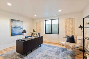 Office with light wood-style flooring and recessed lighting