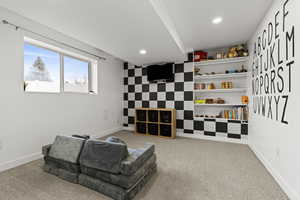 Sitting room featuring an accent wall, recessed lighting, and light carpet