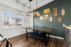 Dining room featuring dark wood-style flooring and vaulted ceiling