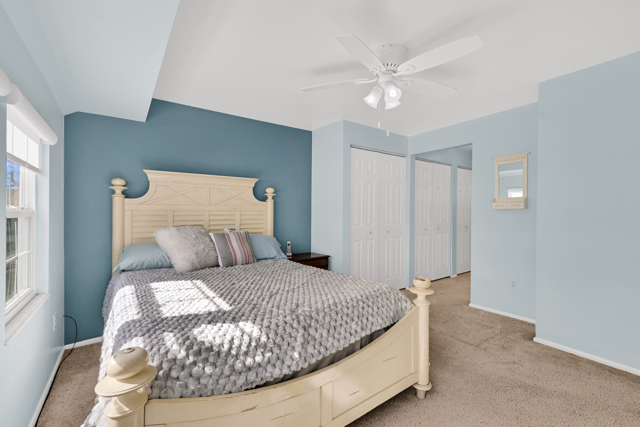 Carpeted bedroom with multiple closets and a ceiling fan