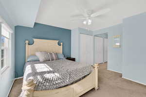 Carpeted bedroom with multiple closets and a ceiling fan