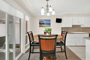 Dining area with a chandelier, light tile patterned floors, and ornamental molding