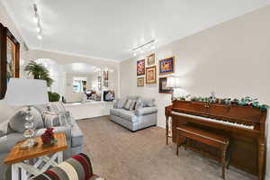 Living area featuring track lighting, crown molding, arched walkways, and carpet floors